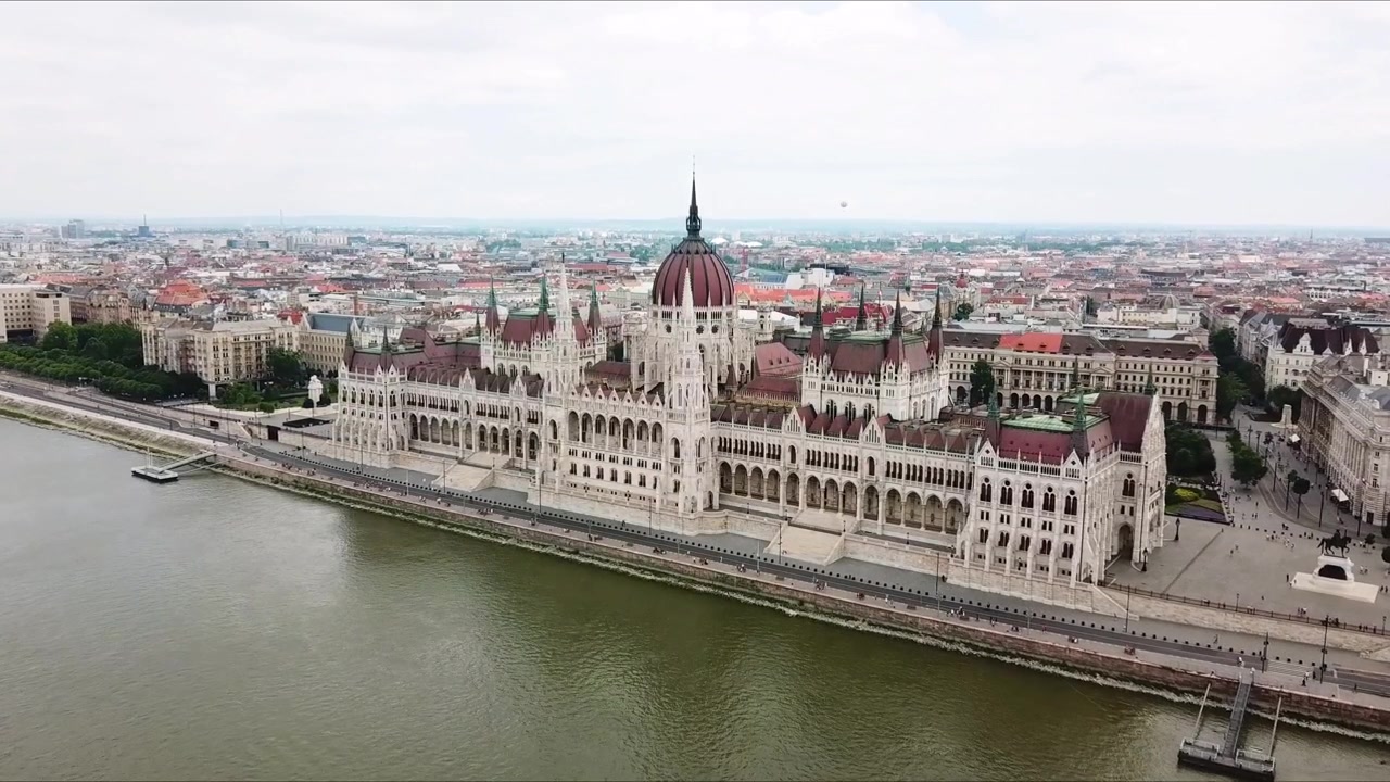 Vista aerea che cattura l'edificio del Parlamento ungherese, un esempio iconico di architettura neogotica e neorinascimentale lungo il fiume Danubio a Budapest, Ungheria, ripresa aerea di apertura