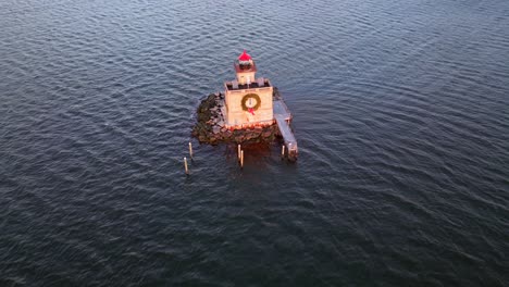 an aerial view of the huntington harbor lighthouse on long island, ny at sunset, with a christmas wreath on it