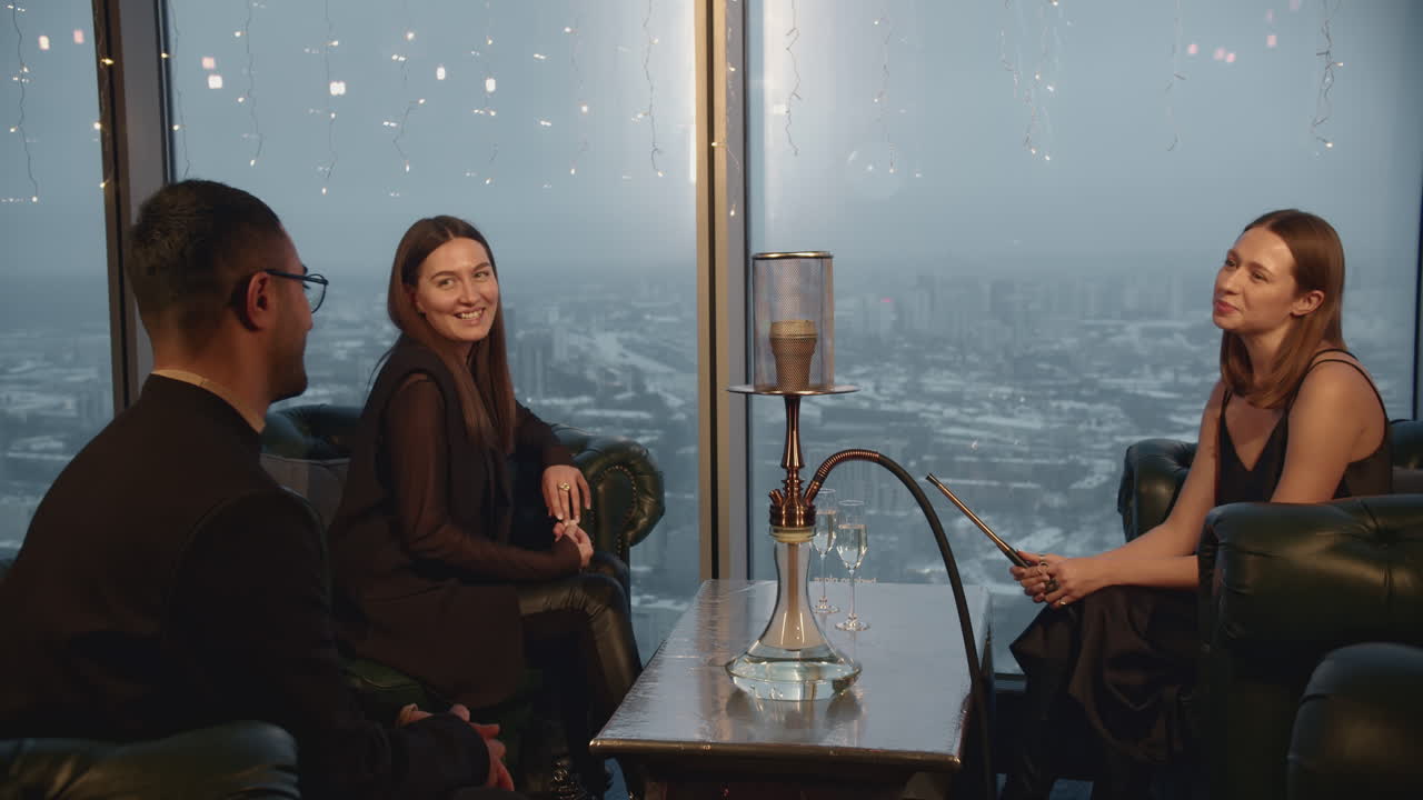 amigos disfrutando de un narguile en un restaurante de tejado de gran altura