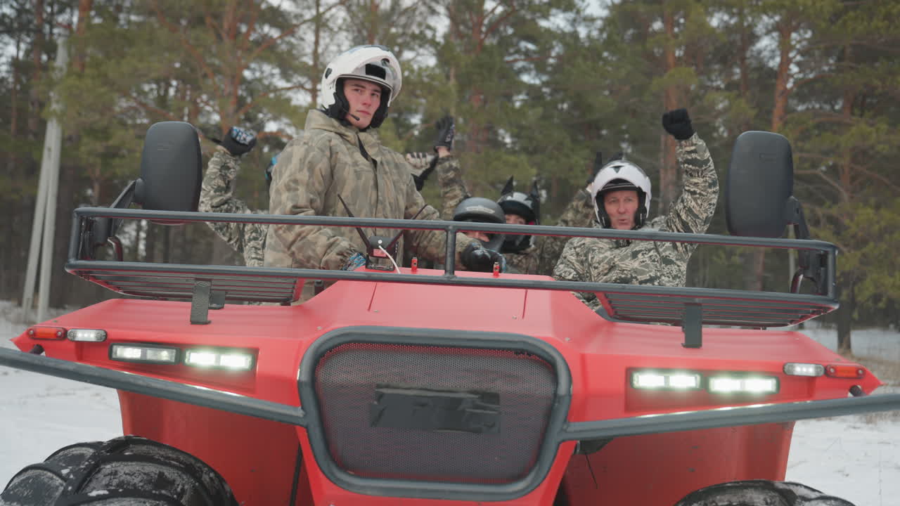 To ryttere på rød ATV signalerer. Guide-duo blinker med forlygter og vinker, camouflagejakker og hjelme, skarpt vinterlys, skovstiscene, smil og klar energi til en ekstrem tur