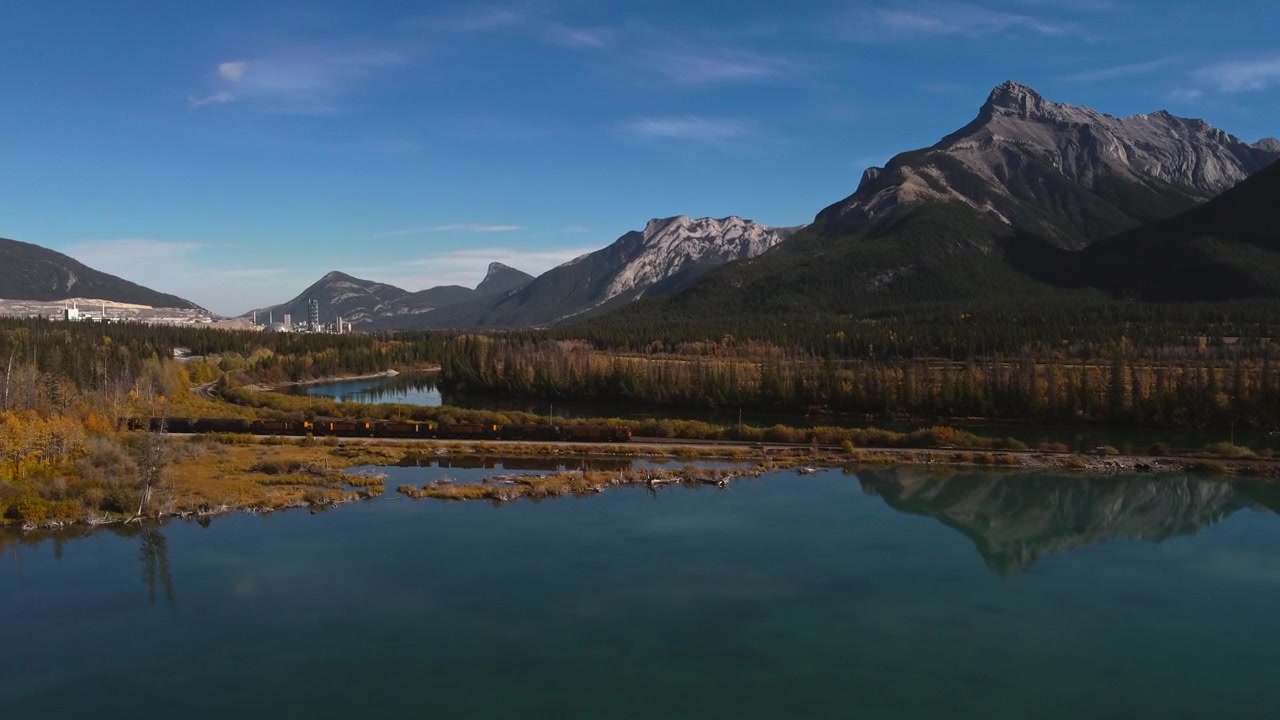 Lago con montagne, fabbrica, treno e approdo