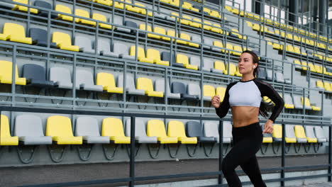 Chica-Muy-En-Forma-Usando-Airpods-Corriendo-En-El-Estadio-Por-La-Mañana