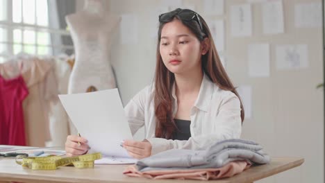 female designer thinking and drawing pencil sketches of clothing