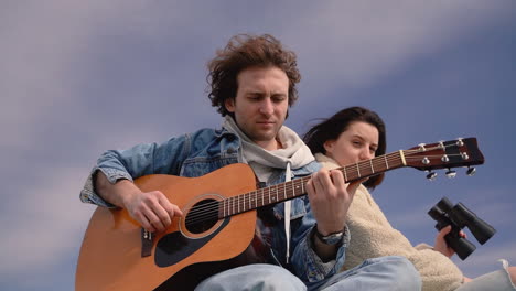 a young boy plays the guitar and a young girl looks around with a pair of binoculars on the roof of a caravan 3