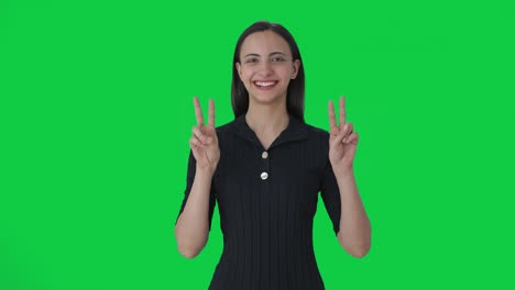 Happy-Indian-female-news-anchor-showing-victory-sign-Green-screen