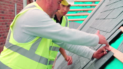 construction worker with apprentice laying slate tiles