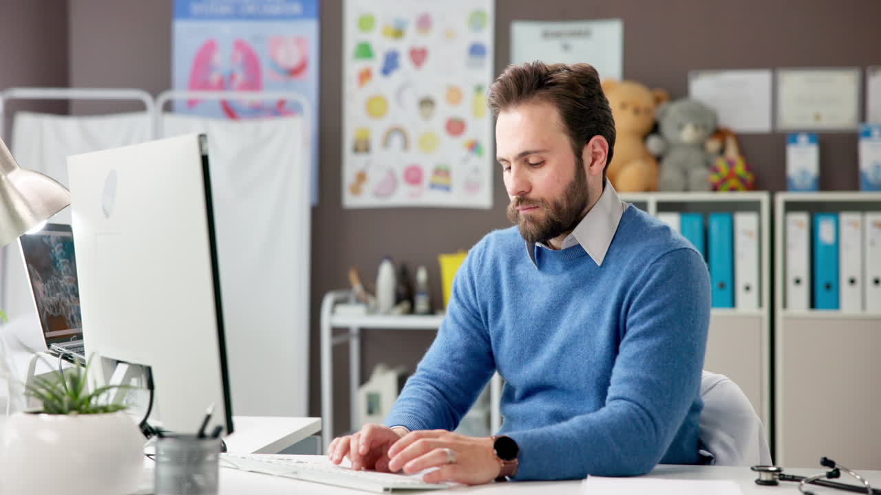 Læge, der arbejder ved sit skrivebord på sit kontor