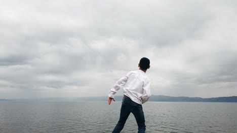 children stand on the shore of the pond and throw stones, slow motion