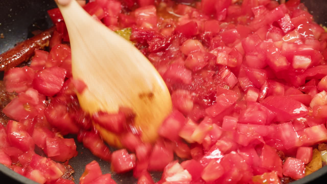 Cooking diced tomatoes with a wooden spoon
