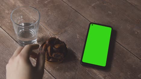 high angle shot of lantern water and dates with a green screen phone