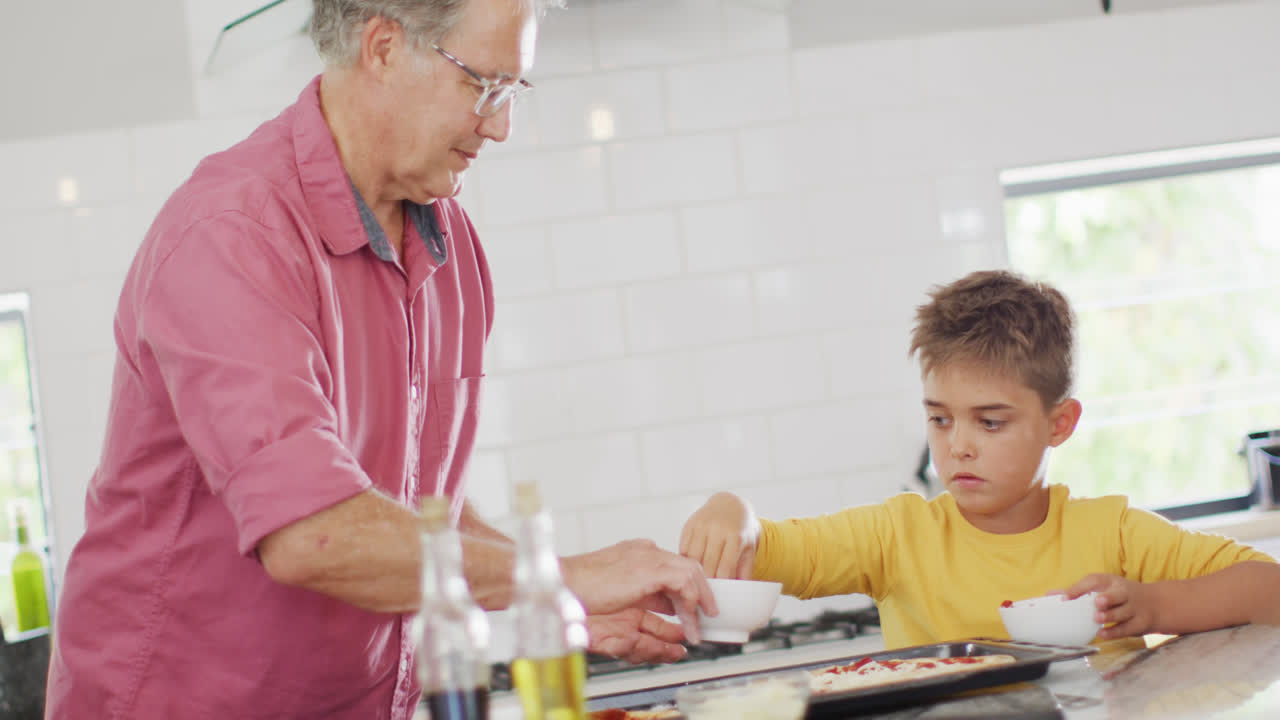 feliz abuelo caucásico y nieto haciendo pizza en la cocina, cámara lenta