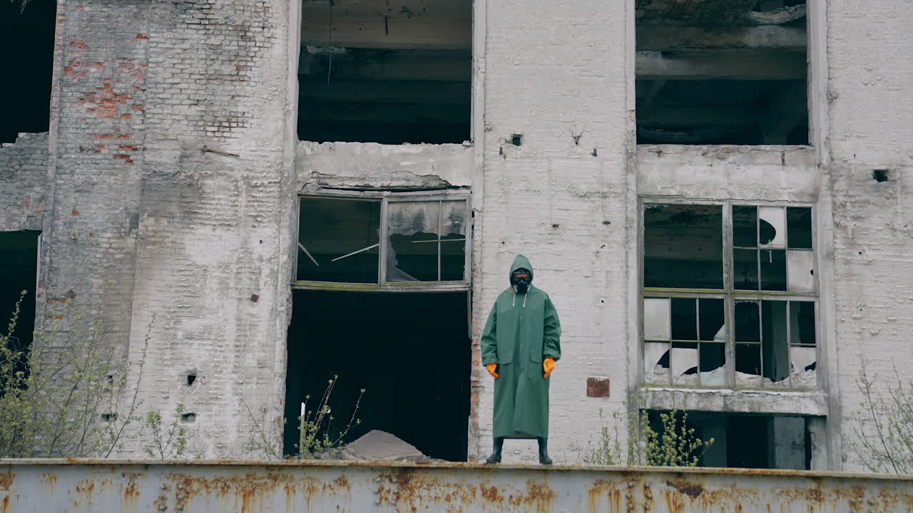 Stalker in military protective clothing. Lonely human in protective gas mask and military clothes walking on old factory