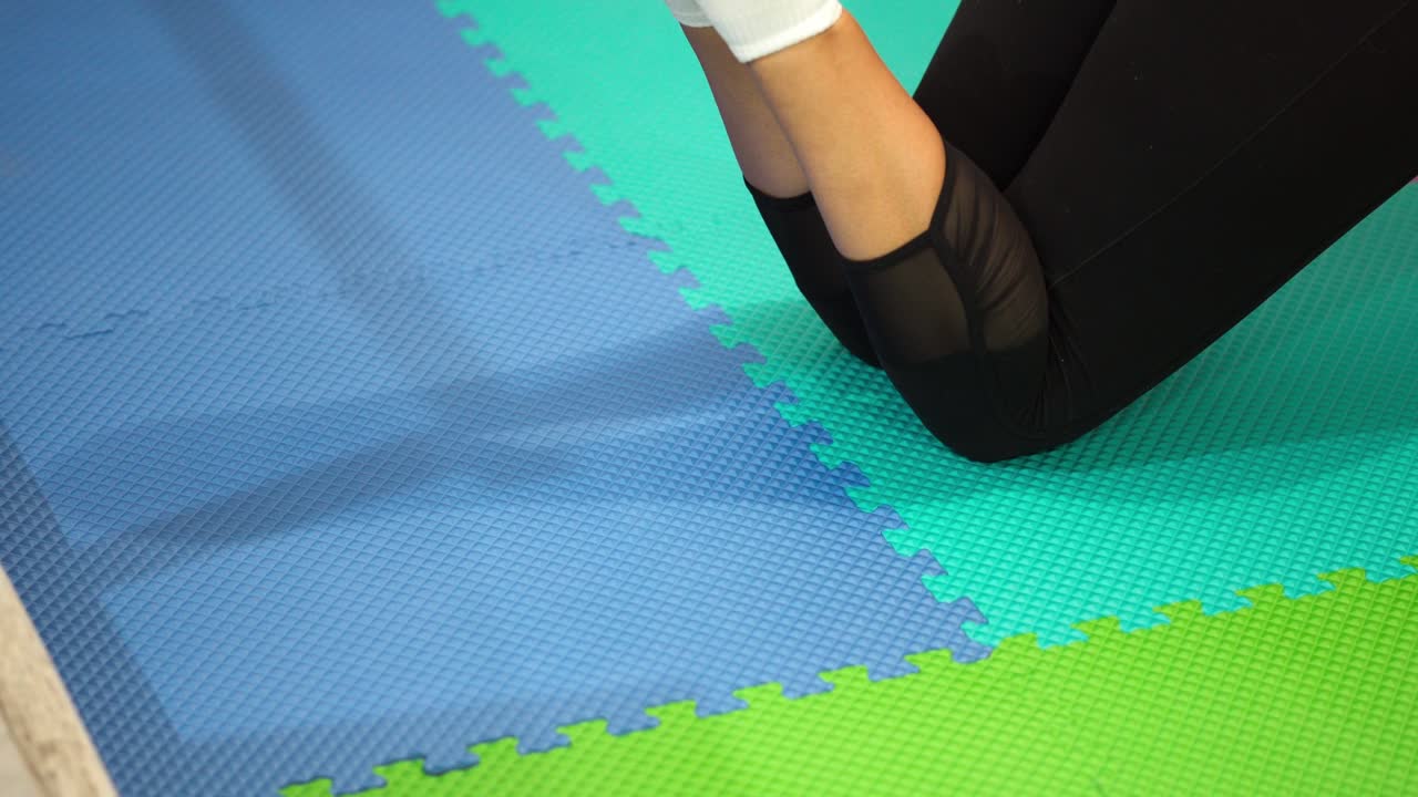 Woman lifting legs on colorful mat in physiotherapy or workout session, camera fixed