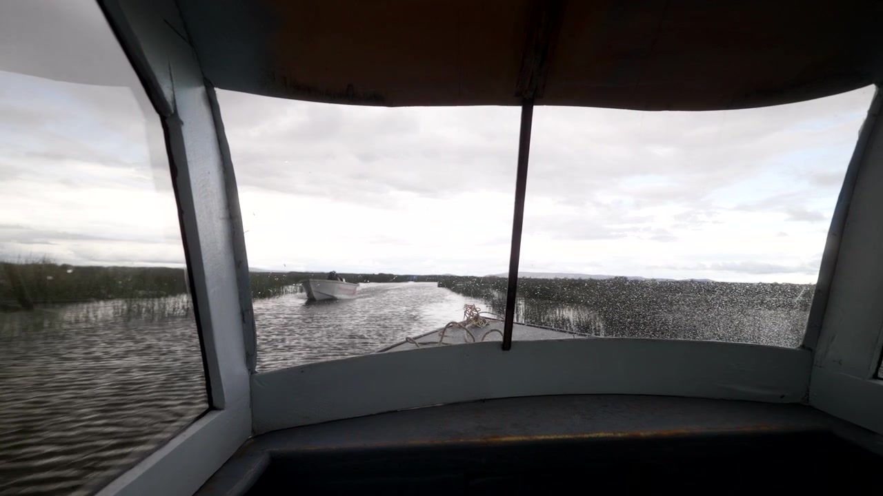 Point-of-view from inside a speedboat travelling across a scenic lake under cloudy skies, creating an immersive travel and adventure perspective from onboard the vessel