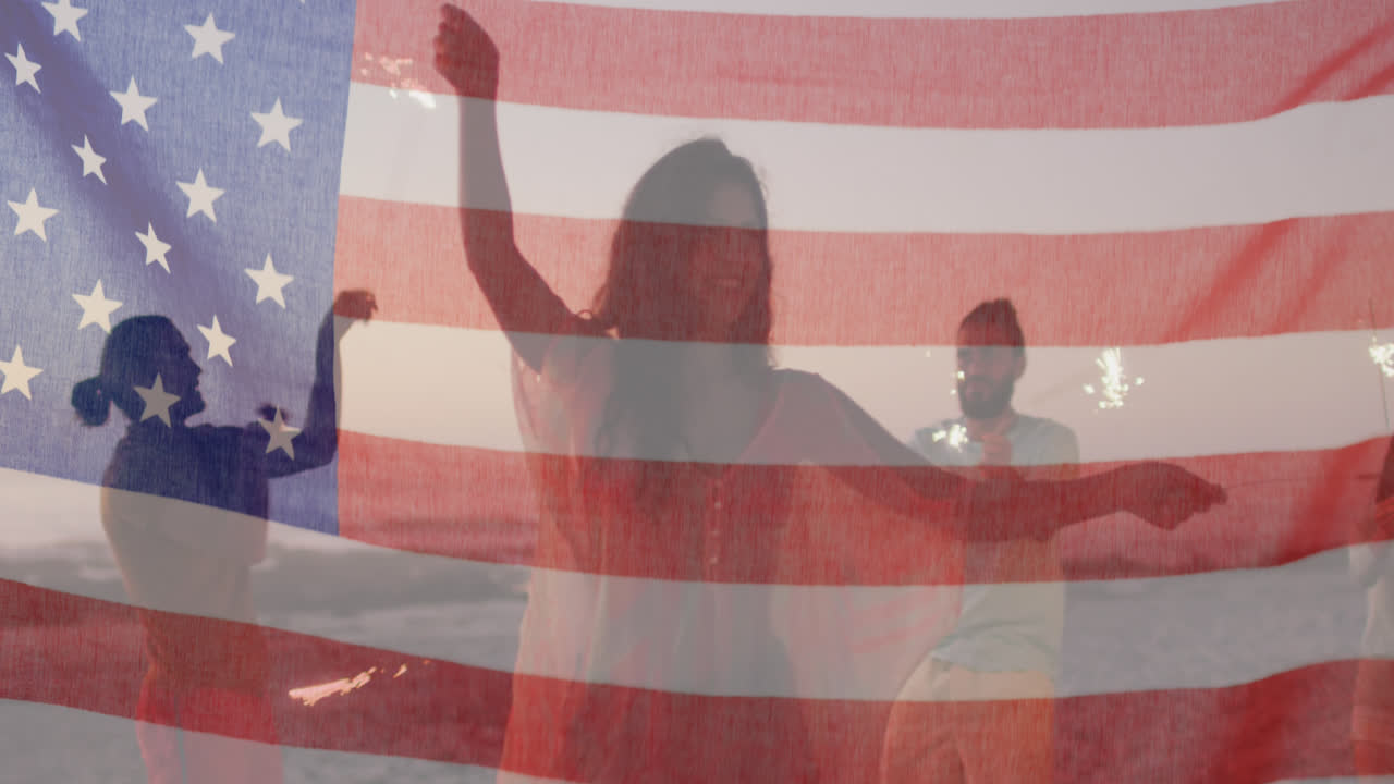 animación de la bandera estadounidense ondeando sobre amigos usando chispas en la playa