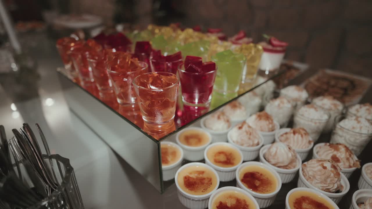 Wedding dessert table with assorted colorful jellies and creamy brûlées in elegant glassware