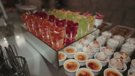 wedding dessert table with assorted colorful jellies and creamy brûlées in elegant glassware