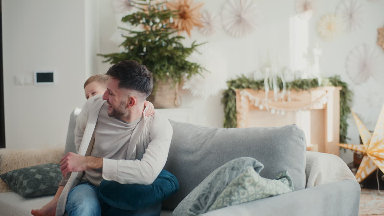 어린 소년은 아버지의 등에 뛰어들어 크리스마스를 즐기고 함께 놀고 있습니다.