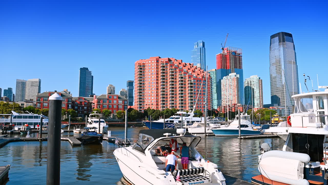 Jersey City, USA, 1 July 2025: Walking by the berths in Jersey City. Watching diverse boats at the piers. Beautiful buildings at backdrop