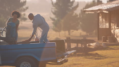 group of friends unloading backpacks from pick up truck on road trip to cabin in countryside