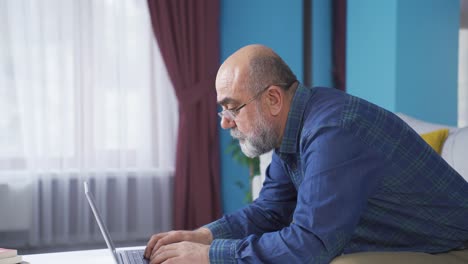 un anciano trabajando en una computadora portátil con gafas.
