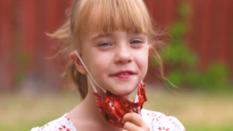 happy little girl takes off her mask and then puts it back on