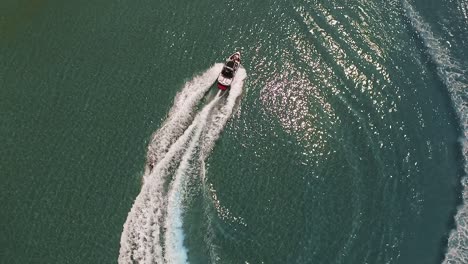 il motoscafo tira il wakeboarder attraverso l'acqua verde dell'oceano, l'antenna circolare sopraelevata