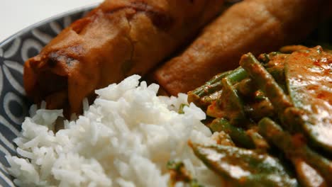 curry de verduras rojas tailandesas con arroz y rollos de primavera