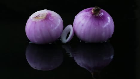 Gotas-De-Agua-Y-Anillos-Cayendo-Sobre-Cebollas-Rojas-Crudas,-Foto-De-Estudio