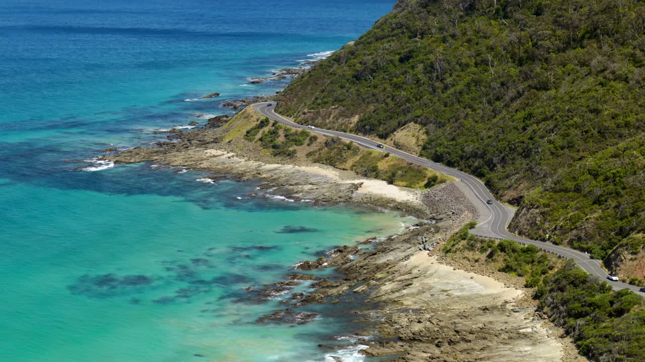 Cars driving along the scenic Great Ocean Road, showcasing the stunning coastline and vibrant landscape of one of Australia's most iconic roads.