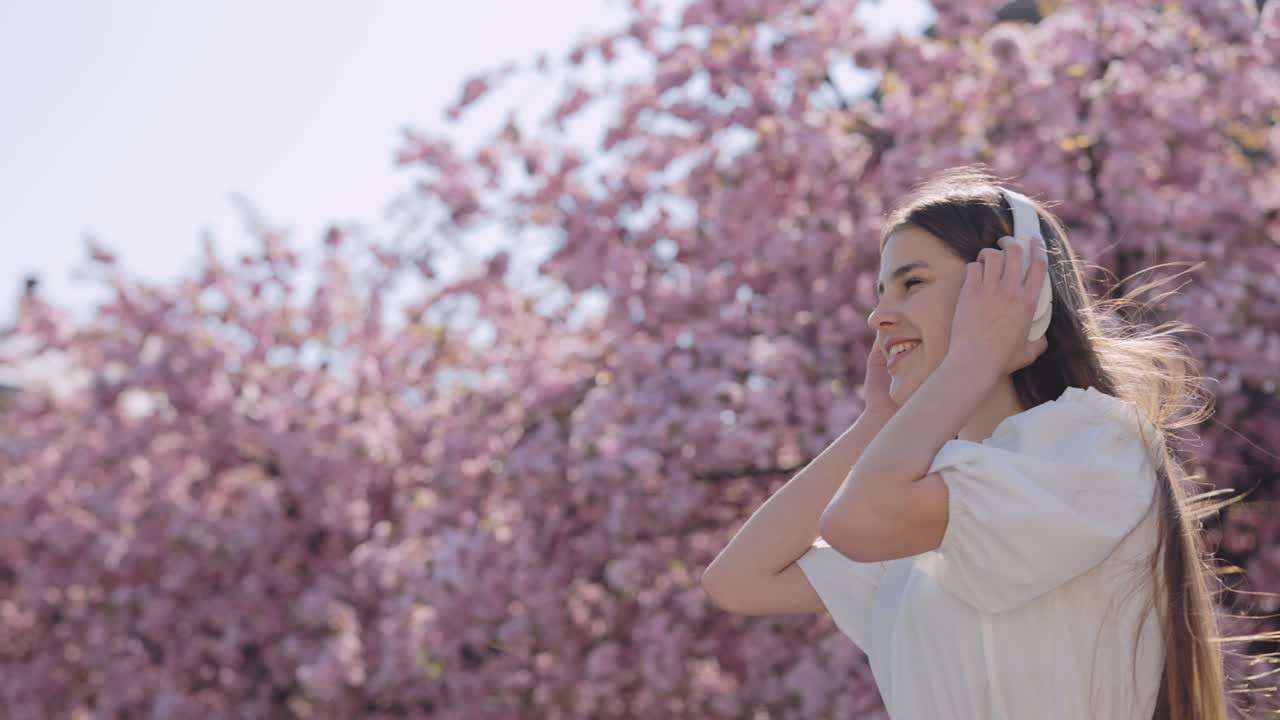 Woman enjoying music under cherry blossoms