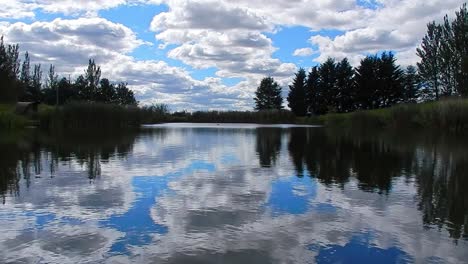 Ruhiges-Blaues-Seewasser,-Spiegelreflexion,-Heller,-Malerischer,-Bewölkter-Himmel