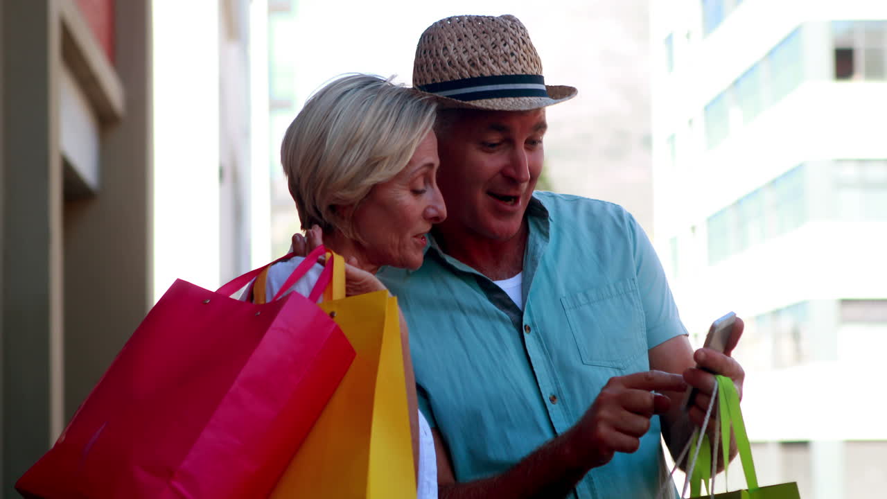 pareja feliz en el día de compras mirando el teléfono inteligente