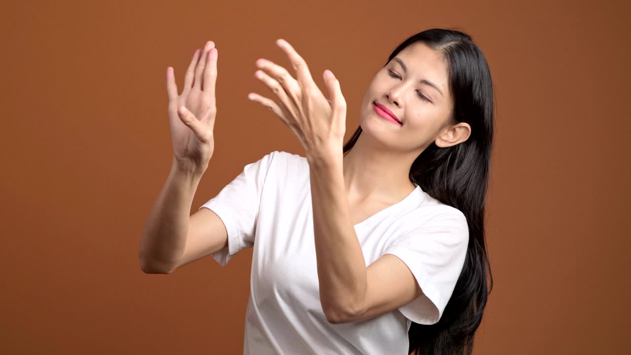 태국 전통 댄스: 화이트 티셔츠를 입은 태국 여성이 카메라 앞에서 태국 댄스를 한다.