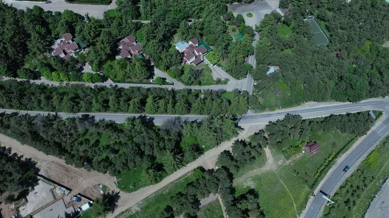 drone disparar alrededor de la ciudad de tbilisi en el lado de la naturaleza de la ciudad para un coche que pasa por la carretera con un montón de árboles verdes en el lado del drone