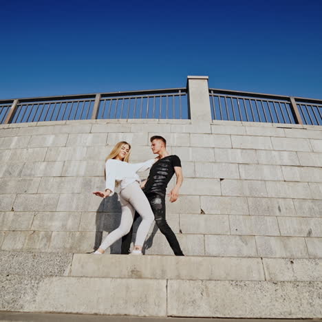 passion dance of young couple. talented teenage boy and girl performing modern dance near the grey wall outdoors. view from below.