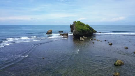 reveal forward drone shot of tropical beach with group of coral rocks hits by the wave and blue sky on the background