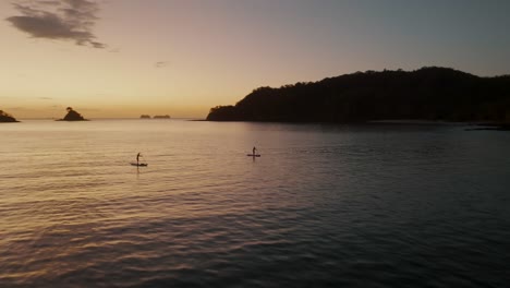 Dos-Personas-Remando-Al-Atardecer-En-Guanacaste,-Costa-Rica---Toma-Aérea-De-Drones