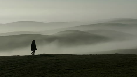 person walking on a foggy hill landscape
