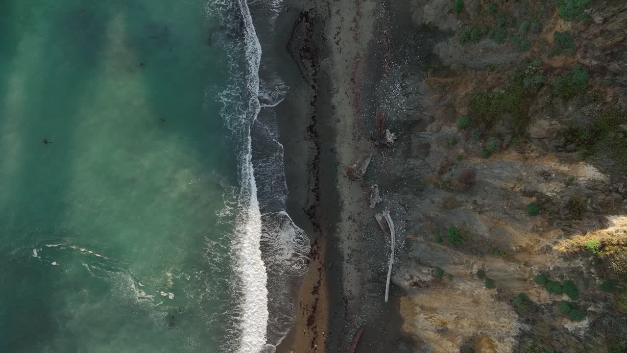 vista aérea de arriba hacia abajo de las olas de la costa oeste rompiendo en la costa erosionada y empinada