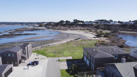 Slow-rise-over-homes-reveals-tidal-flats-and-rocky-shoreline-of-Bandon-Oregon