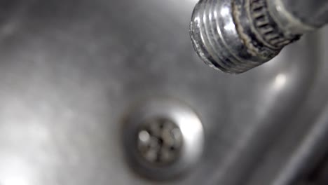 dirty tap, sink, drain and dripping water, cinematic background, focus change from tap to sinkhole