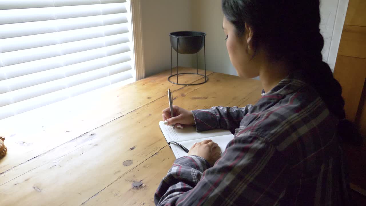 inspiradora joven puertorriqueña mujer escribiendo viaje diario de salud mental en diario personal, vista por encima del hombro