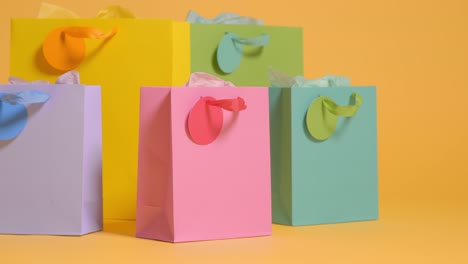 studio shot of colourful birthday party gift bags against yellow background 2