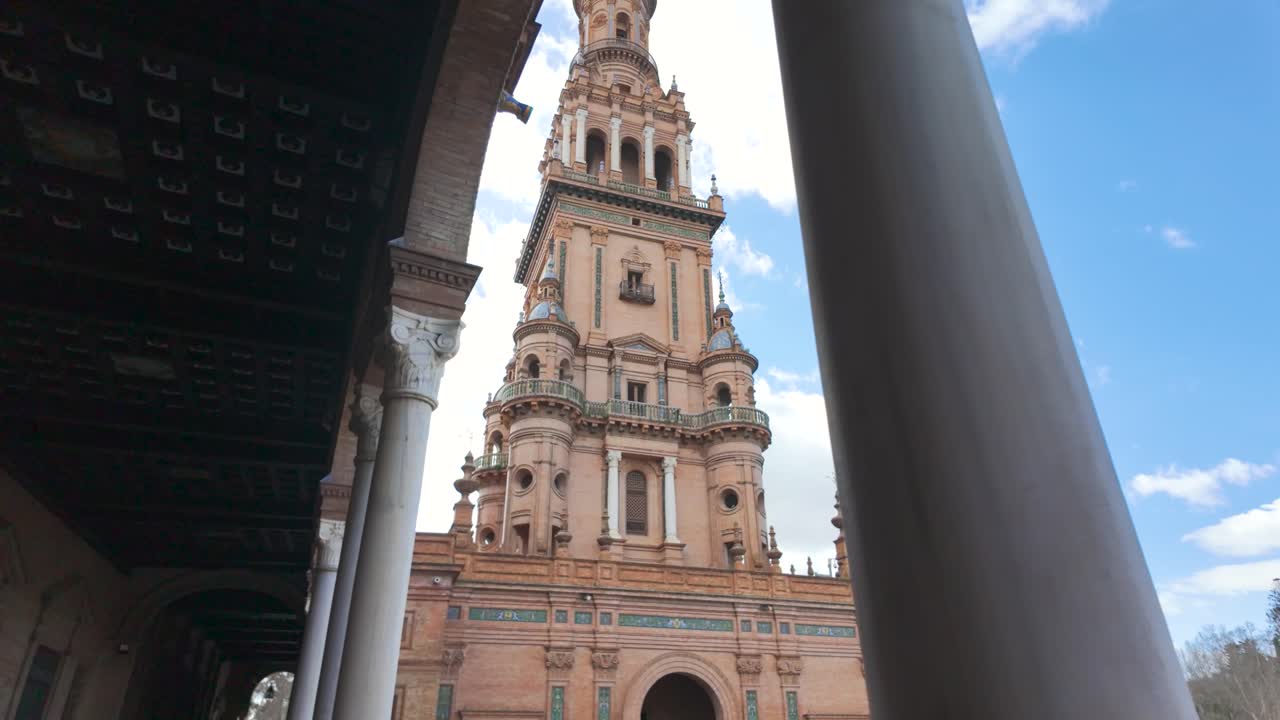 Looking up at the ornate tower of Plaza de España in Seville against a bright blue sky