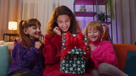 Three-siblings-children-girls-opening-gift-box-with-excited-surprised-face,-birthday-glowing-present