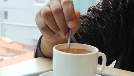 Person-hand-stirring-coffee-with-spoon