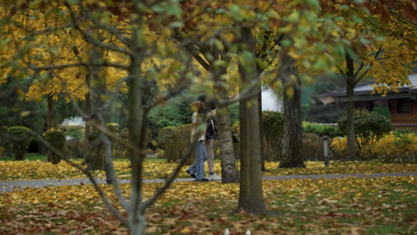 stylish young lovers walking arm in arm in foliage park