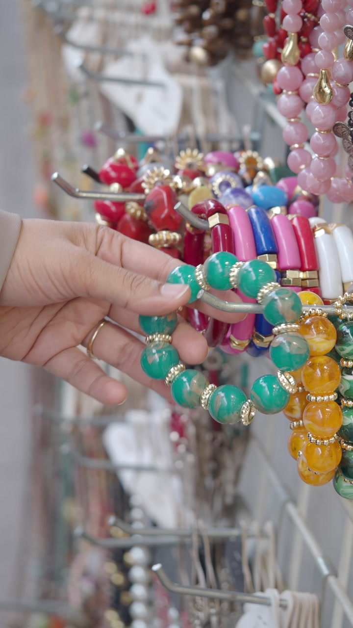 Woman's Hand Examining Colorful Bracelets on Display