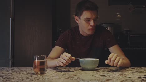 man eating food from a bowl in a home kitchen - close up